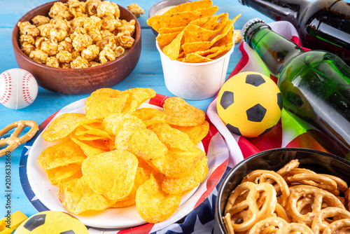 International football soccer championship background, soccer matches cheering concept with beer bottles, party snacks chips, popcorn, pretzel, nuts, whistle and soccer ball, american flag, copy space