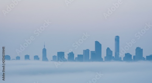Foggy cityscape view shows skyscrapers rising above misty morning landscape