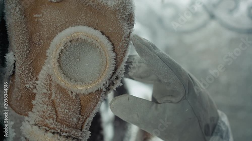 Frost covered gas mask gloved hand researcher inspecting sample in abandoned house after nuclear winter, closeup of icy respirator filter and corroded strap, tense laboratory atmosphere suggesting