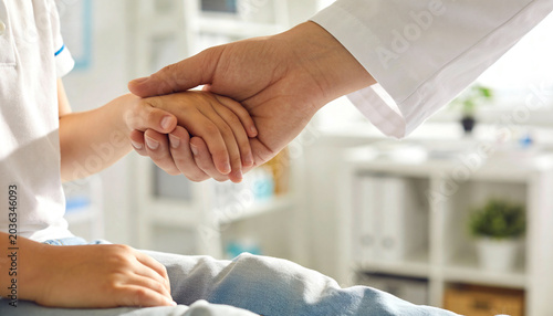 Doctor gently holding child patient hand in clinic in a pediatric healthcare support, compassion and medical trust representation.