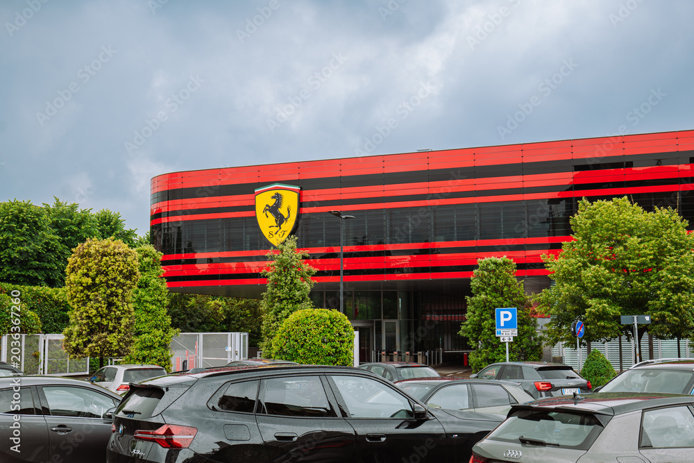 Naklejka premium Maranello, Italy, May 15, 2026. The Iconic Ferrari Scuderia Logo and Modern Glass Facade of the Gestione Sportiva Complex