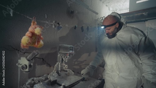 Scientist in hazmat suit examines frozen sample inside abandoned frostcovered laboratory headlamp illuminates hanging chicken carcass and dusty equipment while researcher documents contamination