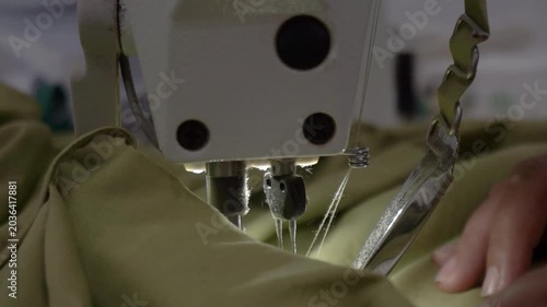 Tailor's hand stitching fabric with sewing machine in a clothing factory, close up footage