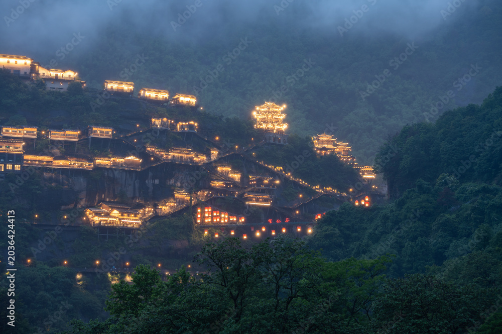 Fototapeta premium Beautiful traditional architecture illuminated with warm lights at night in the scenic mountains of Wangxian Valley in Jiangxi China