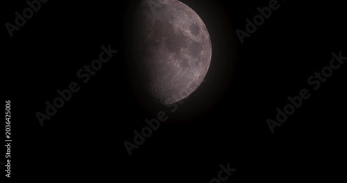 Detailed close-up of the moon in phases moving through pitch black night sky with light glow, ideal for overlay.