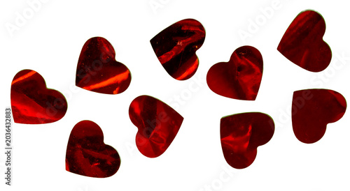 Red hearts made of metallic paper on a green surface.