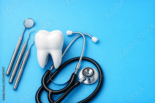 A collection of dental tools and equipment, including a stethoscope, on a blue background.