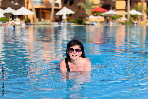 Relaxing Woman in Sunglasses Lying in a Shallow Pool, Enjoying Her Vacation Under the Sun, Blissful Moments of Leisure and Serenity.