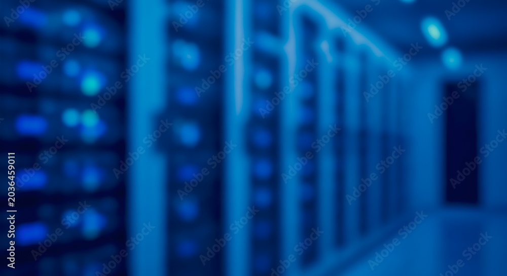 Fototapeta premium Blurred computer server racks in a modern data center representing digital information storage and high-speed networking.
