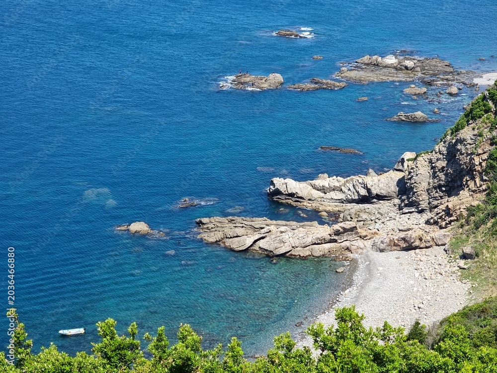 Obraz premium 透明な青い海と岩場が広がる海岸風景