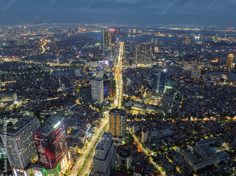 Obraz premium Night aerial panorama of Nguyen Chi Thanh Street with illuminated traffic corridors and dense Hanoi urban skyline.