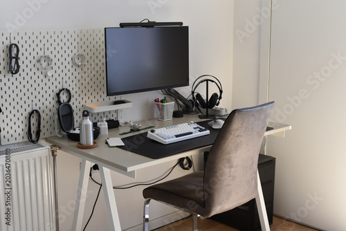 Foto Brightly lit home office desk with monitor and pegboard