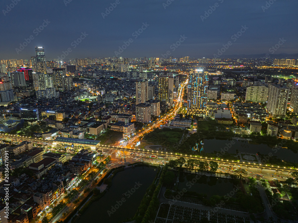 Fototapeta premium Night aerial view of Ho Tung Mau Street in Cau Giay District with illuminated traffic corridors and dense Hanoi skyline.