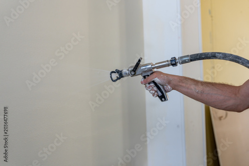 Application mécanique d’un revêtement mural par projection airless lors de travaux de finition intérieure sur un chantier de rénovation.