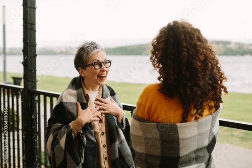 Generational women laughing together wrapped in plaid blankets