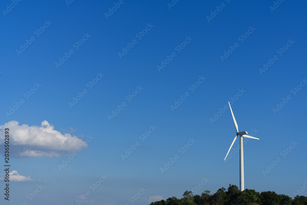 Obraz premium Wind turbine for renewable energy on a hill under a beautiful clear blue sky.