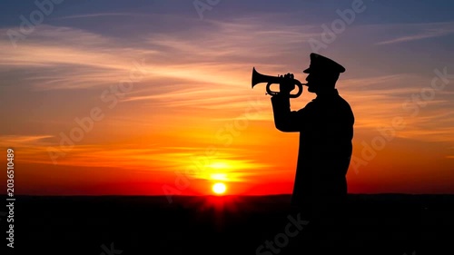 Silhouette of a military bugler playing taps during a sunset memorial service.