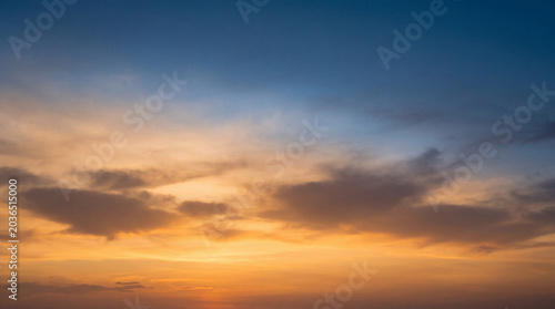 Bild auf Leinwand Dramatic and vibrant sunset sky with rich orange and blue hues, featuring dark, silhouetted clouds overhead