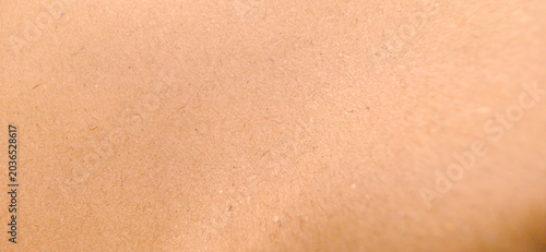 Close-up abstract background of a smooth, light peach or pale brown surface with a fine, natural grainy texture resembling craft paper.
