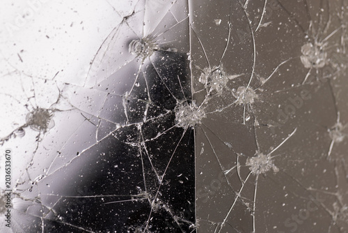 Фотография thin broken glass on black paper, dents and dots on the glass where it broke, wh