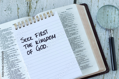 Fotografía Seek first the kingdom of God, inspirational quote in notebook with open holy bible and magnifying glass