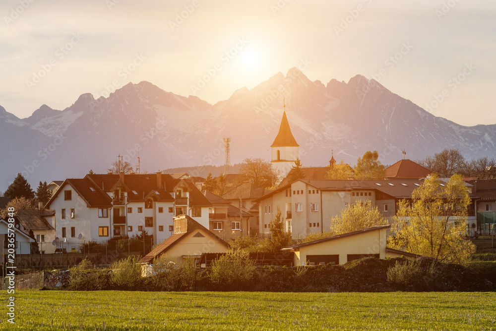 Fototapeta premium Small mountain village at sunset with church tower