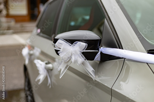 Wedding car decoration with white ribbons and bows on side mirror