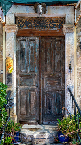 Entrance with stone surround and dilapidated old wooden door at a residential building in the town of Bellapais in Cyprus