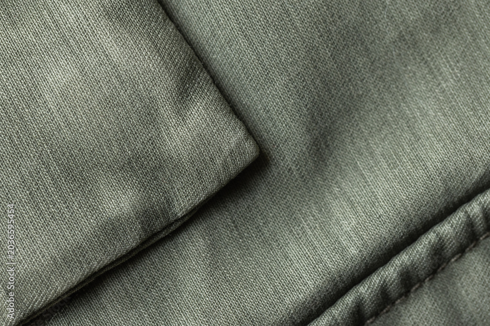 Naklejka premium Close-up of folded green fabric revealing detailed textile texture, padded quilting and visible stitching; versatile background for design, upholstery, fashion, material studies and soft home decor