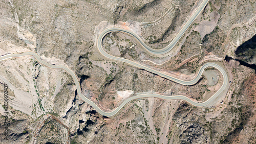 Top-down aerial shot of a winding mountain road forming a zigzag pattern.