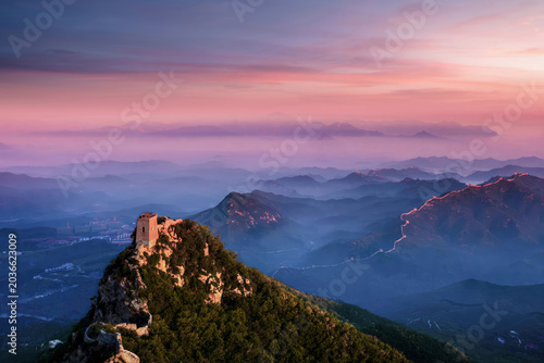 A stunning sunrise over the ancient Xian Nu Lou at Jinshanling, with mist rising from the valleys and the Great Wall stretching into the horizon.