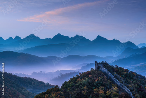 Dawn over Zhuizi Mountain Great Wall in Suizhong, Liaoning, with misty mountains and vibrant autumn forest.