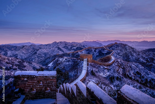 The majestic Great Wall of China at Jankou, covered in snow, with morning light casting a serene glow over the mountainous landscape. Winter beauty in Beijing.