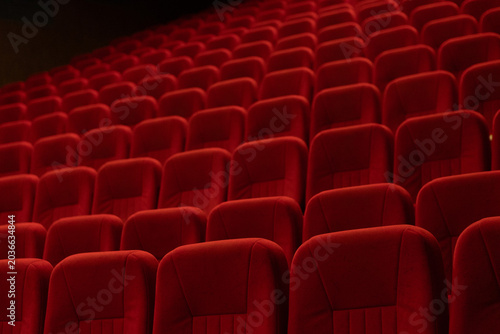 Empty cinema auditorium with rows of red velvet seats and ceiling lights