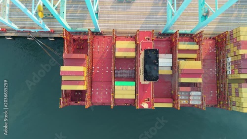 Portsmouth, Virginia, striking 4K top-down aerial video tracking sideways over a massive MSC cargo container ship docked under teal gantry cranes at the Virginia International Gateway (VIG) terminal.