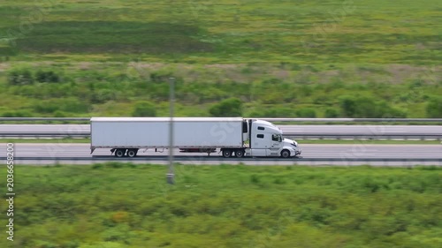 Aerial view of semi-truck driving on busy American interstate freeway. Delivering cargo concept.