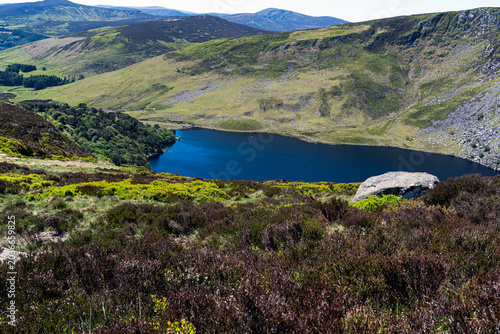 High angle view of the famous Guinness Lake with deep blue water nestled in a valley of Wicklow Mountains on a sunny day