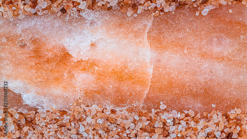 Tableau sur toile Rock salt crystals and large salt block with orange and white tones on a flat su
