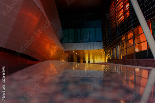 The building's modern exterior with a blue wall and red windows creates a dramatic atmosphere of nightlife and passion.