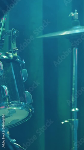 Close up view of drum kit on dark stage. Percussion instrument detail with tom cymbal illuminated by moody purple pink lights. Live music performance atmosphere for heavy metal rock concert