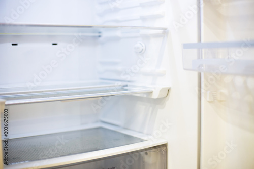 Empty refrigerator interior showing white shelves and lack of food