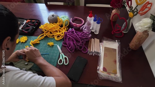 Artisan woman crafting yellow yarn flowers at home