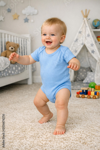 Young child in blue romper smiling and ready to walk. Interior setting with toys and children's decoration.