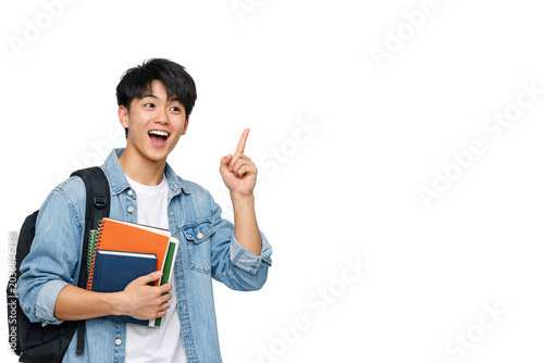 A cheerful student holding a stack of books and pointing with one hand towards the camera.