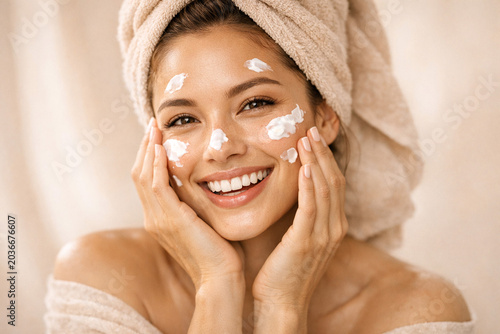 A happy woman putting hand cream on her hands.