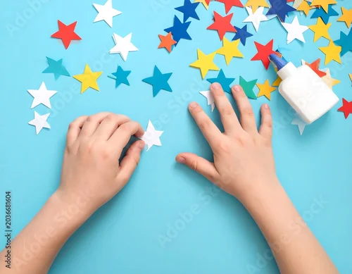 Fototapeta na wymiar Child's hands crafting with colorful star cutouts and a glue bottle on a vibrant blue surface