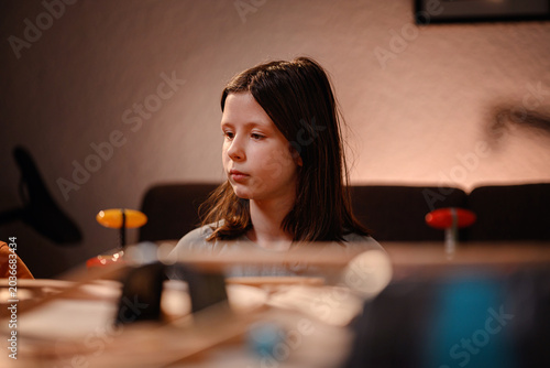 Atmospheric portrait of focused young girl playing with wooden toy railway at cozy home