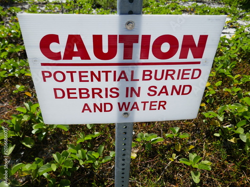 Cuadro en lienzo Caution potential buried debris in sand and water warning hazard sign in nature