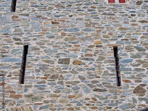 Canvastavla A close-up shot of a rustic medieval stone fortress wall constructed from
irregular, multi-colored fieldstones