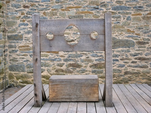 Fotografi A straight-on shot showcases a classic medieval wooden pillory standing on a
timber plank floor